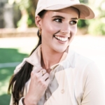 Miss International Australia, Selina McCloskey smiles, wearing a Skye Melody jacket and baseball cap.